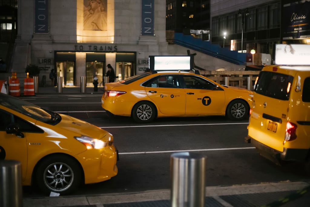 From above of contemporary shiny yellow cabs riding on asphalt roadway in New York at night